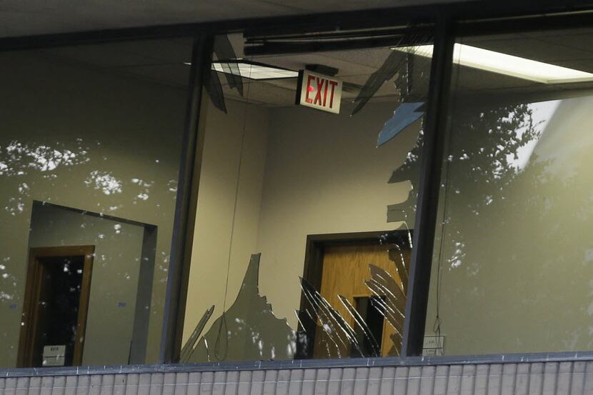 Glass shards are exposed on broken a window of El Centro College in downtown Dallas, Friday,...