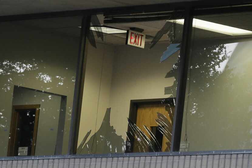 Glass shards are exposed on broken a window of El Centro College in downtown Dallas, Friday,...