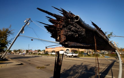 A sheared off utility pole lays over Preston Road in Dallas, near the Preston Royal shopping...