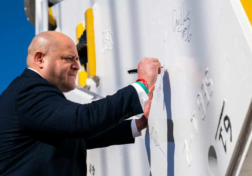 Dallas Mayor Pro Tem Adam Medrano signs the cutter head of a fully assembled tunnel boring...