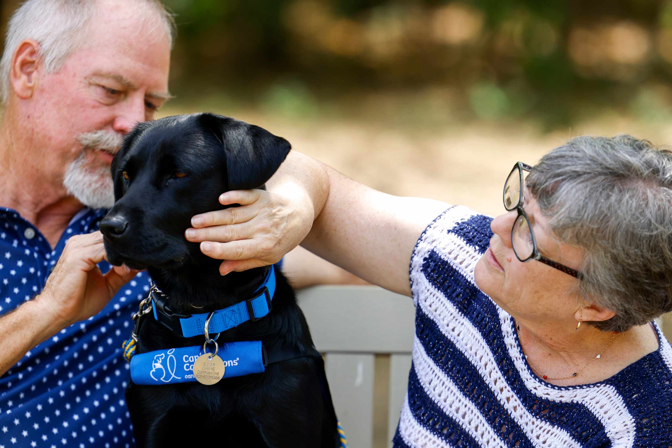 Veteran Kathy Schneider and her husband Ray pets their dog Dakota in between a portrait...