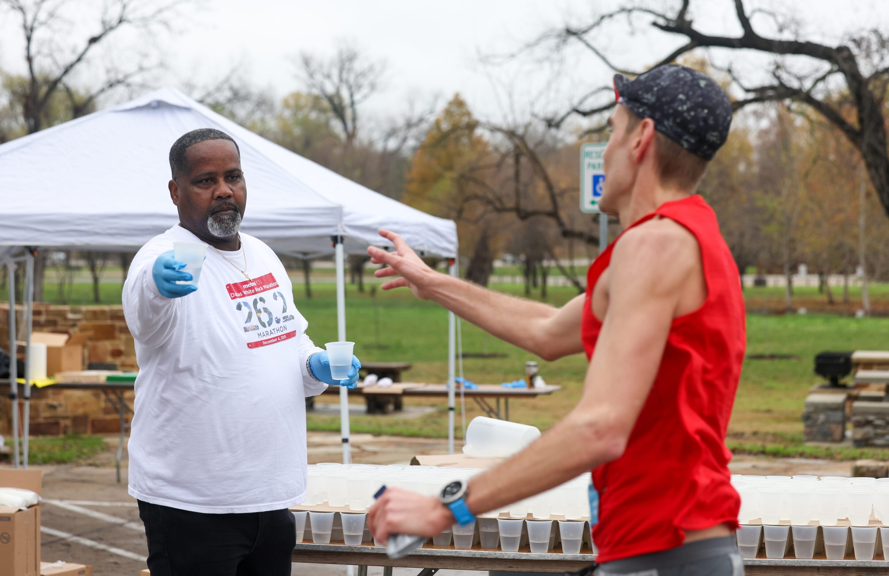 Cliff Piper (left) gives water to runners at the 17-mile mark of the BMW Dallas Marathon on...