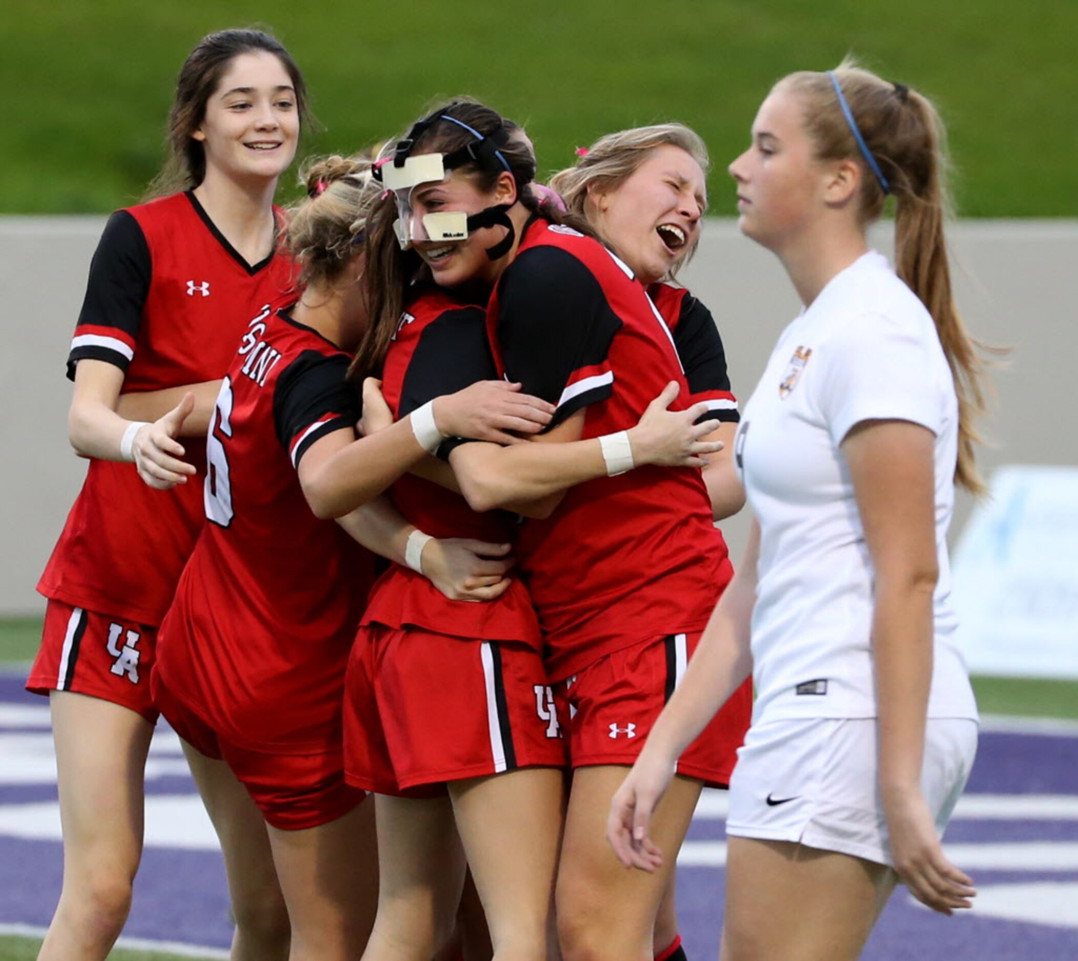 Ursuline Academys Alex Arenas (25), wearing face mask , along with other teammates hug...