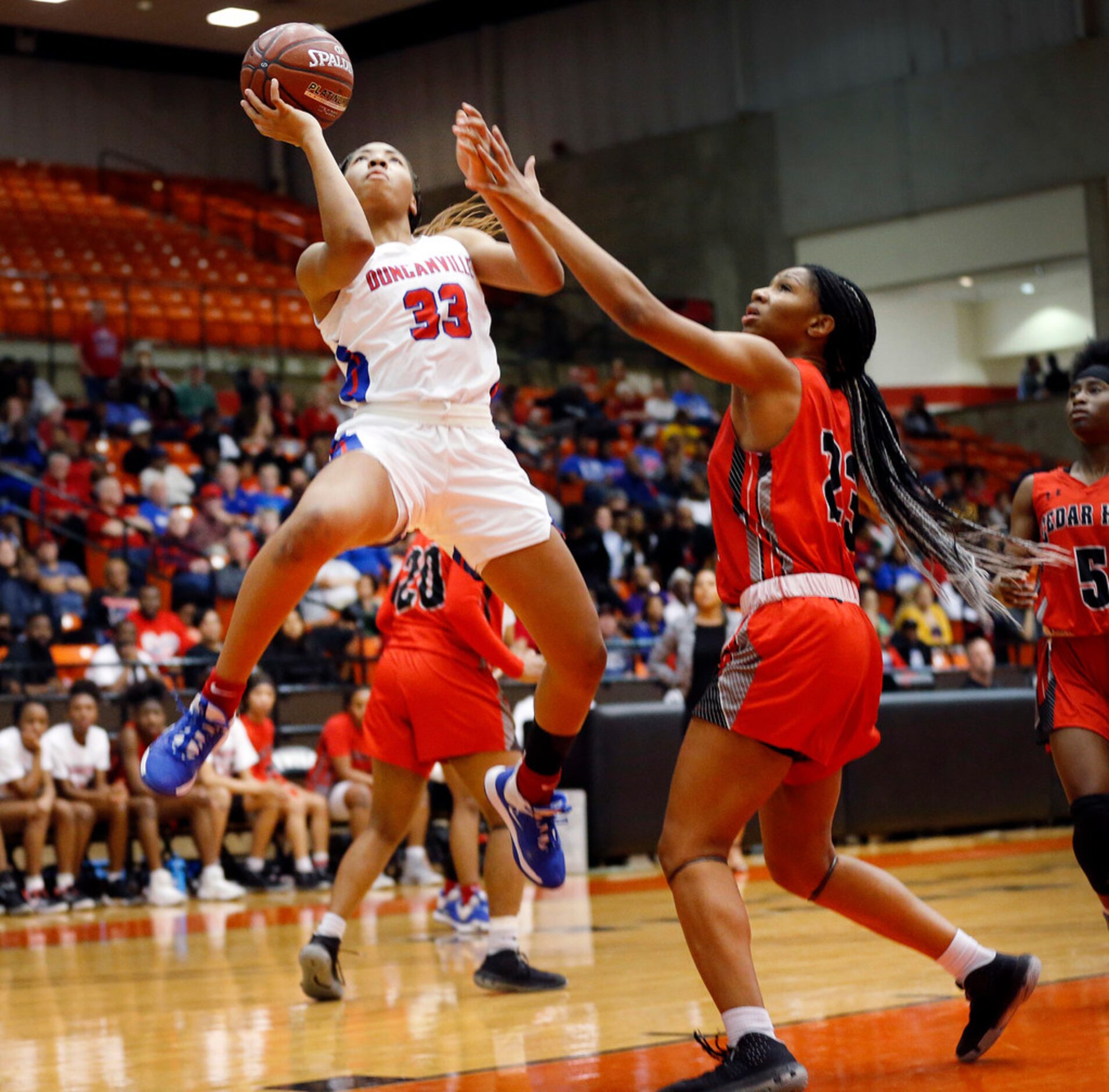 Duncanville's Nyah Wilson (33) lays up a shot past Cedar Hills' Anzhane' Hutton (23) during...