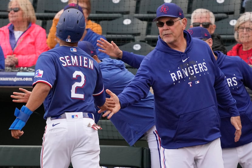 Texas Rangers manager Bruce Bochy celebrates with Marcus Semien (2) after he scored on a...
