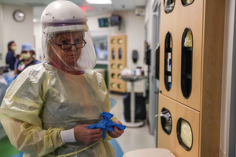 Nurse Lee Ann Carter gets ready with PPE that includes a helmet with a protective shield...