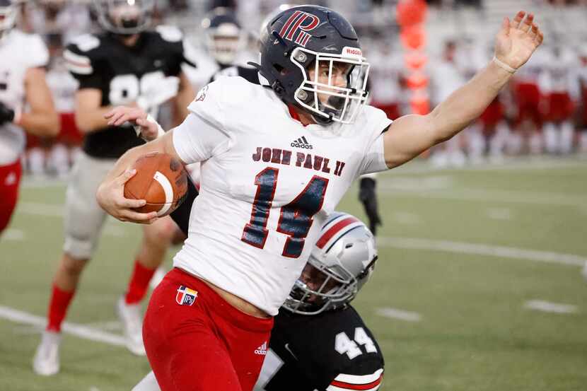 John Paul II High School punter James Knight (14) runs with the football after receiving his...