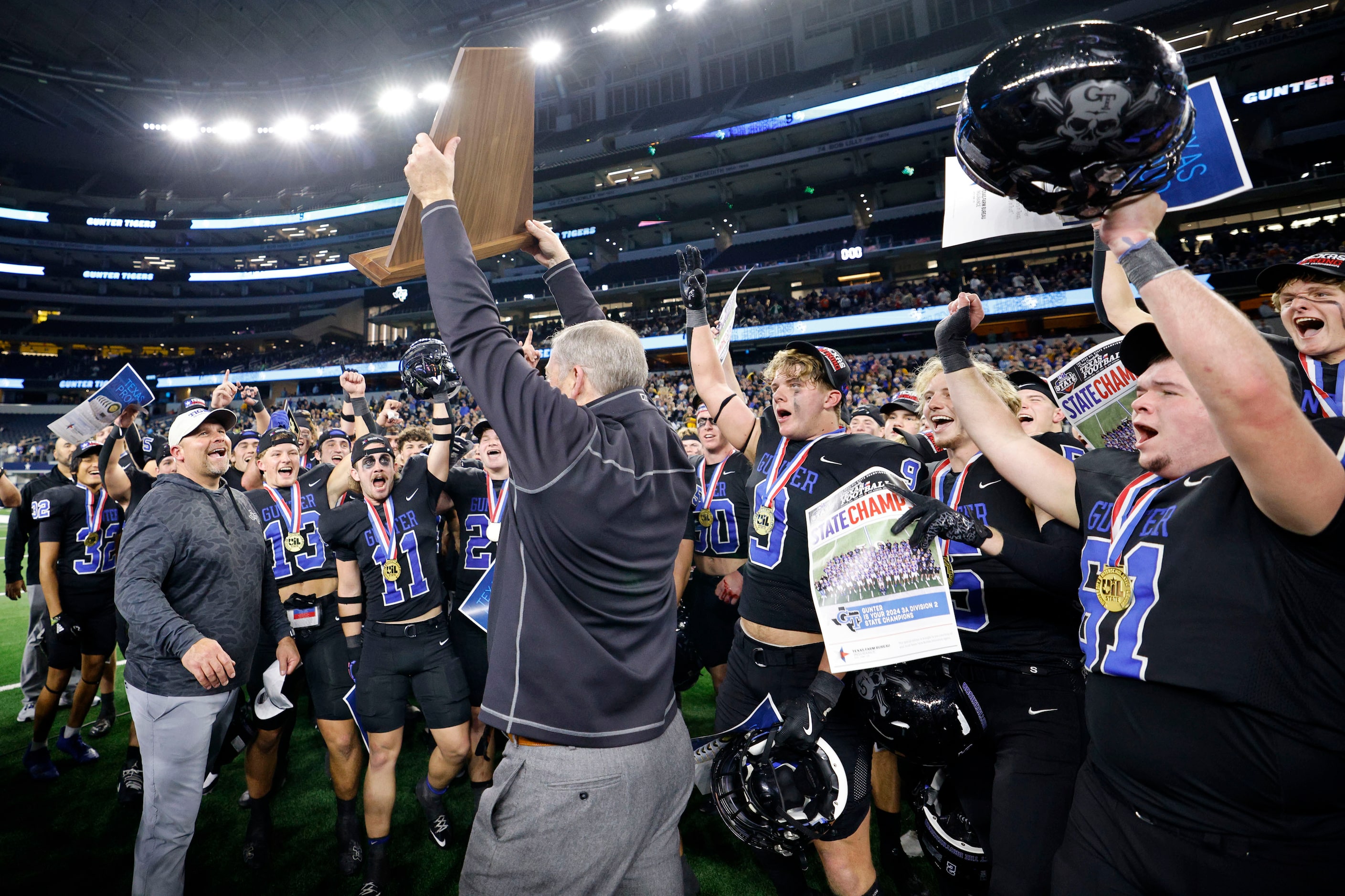 Gunter's head coach Jake Fieszel, left, receives a trophy after their 28-0 victory against...