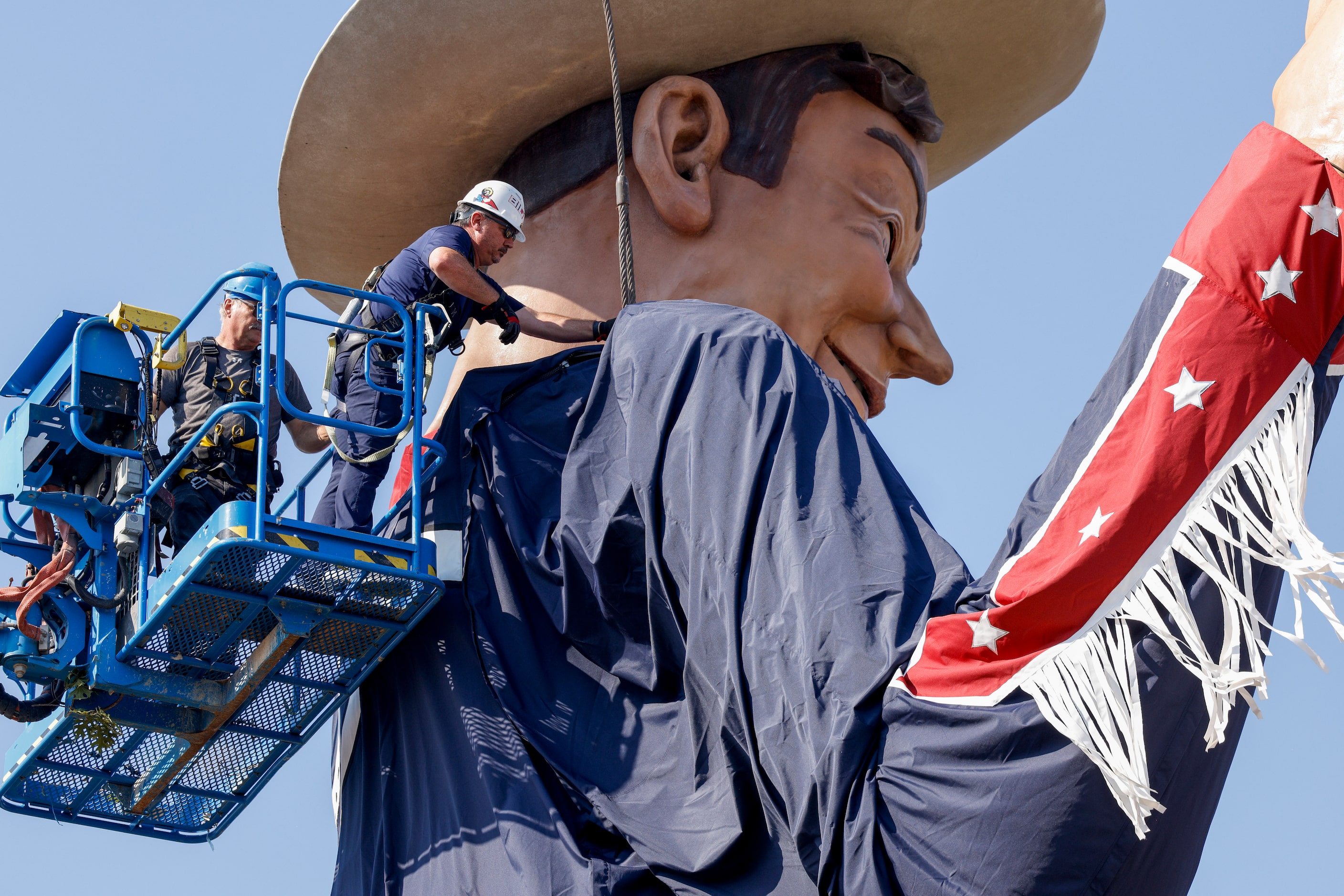 Crews remove one of the steel cables used to lift Big Tex at The State Fair of Texas,...