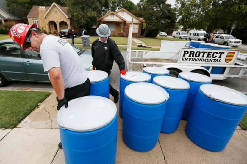 
Workers with Protect Environmental Services moved barrels Monday to the back of an...