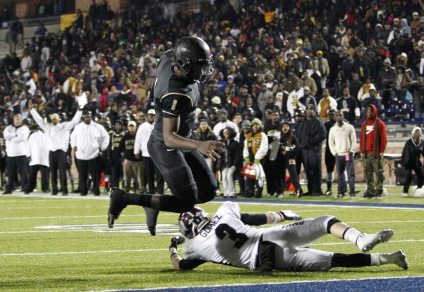 South Oak Cliff quarterback Kenneth Arthur II (1) hurdles Wylie defensive back Ramiro Gomez...