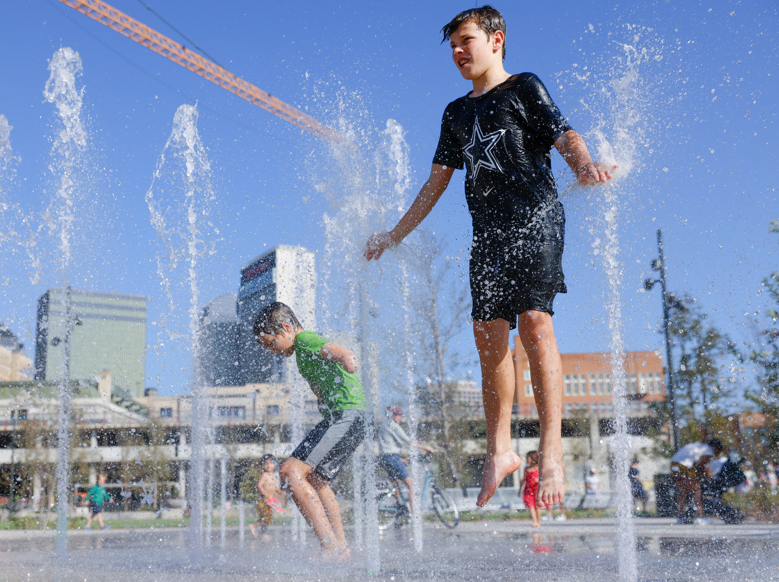 Sage Trulson, (left), 9, and his brother Creed, 13, play in the water fountain during the...