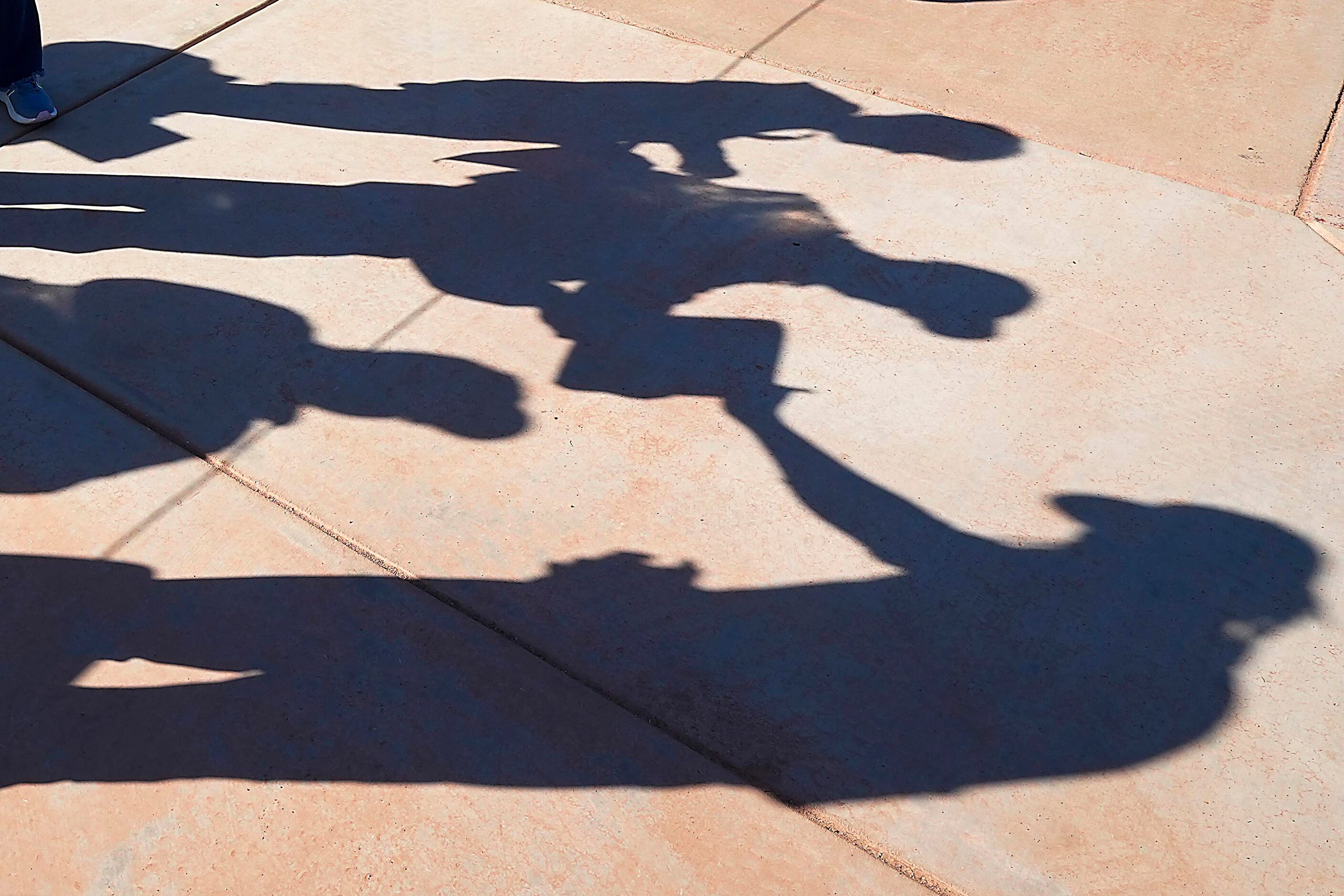 Texas Rangers pitcher José Ureña casts a shadow as he stops to sign autographs during the...