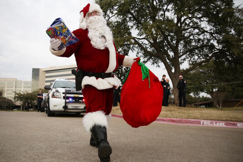 Santa Cop, played by Addison police officer Allen Schieck, hands out gifts to children in...