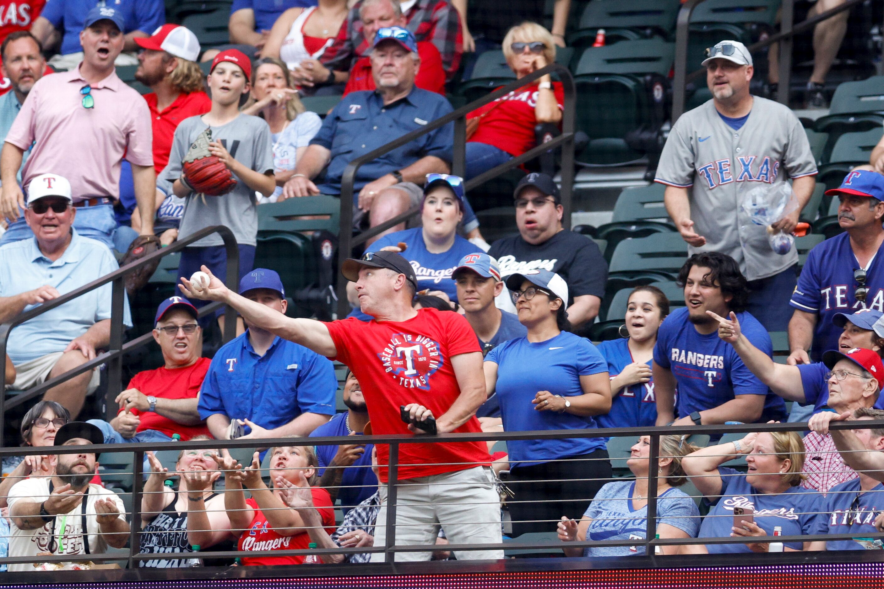 A Texas Rangers fan reaches out to catch a foul ball during the Rangers home opener against...