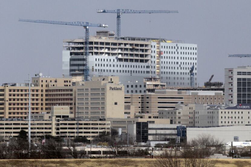 The old Parkland Memorial Hospital is dwarfed by the new Parkland, under construction on...