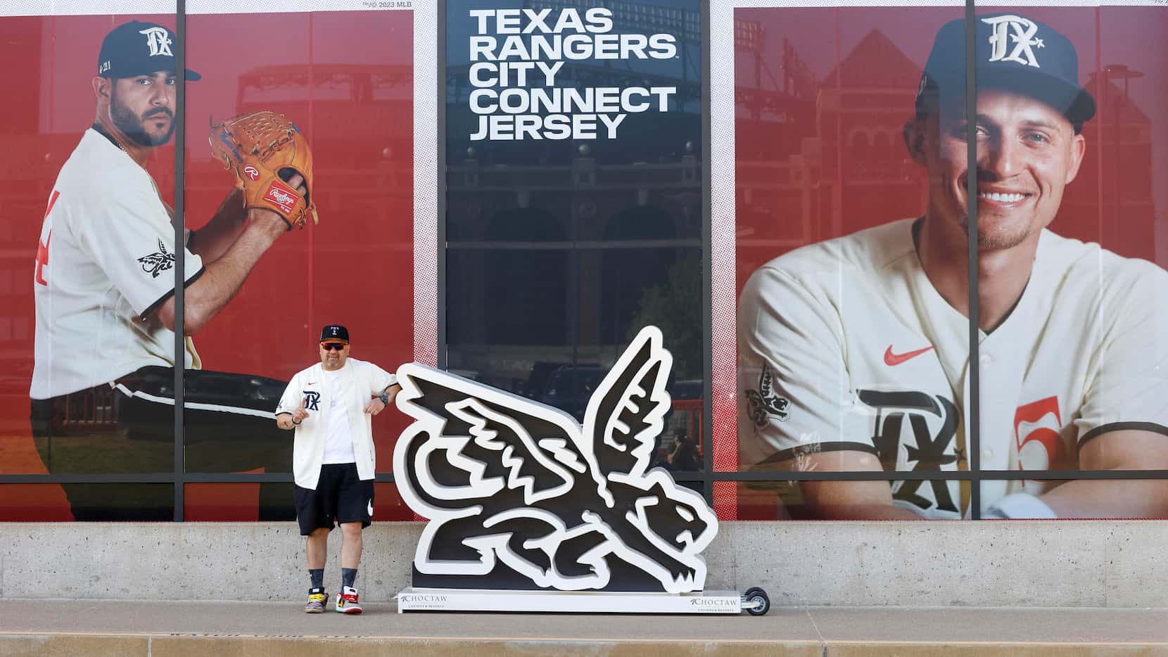 Texas Rangers fan Fernando Mendoza poses next to a new City Connect logo outside Globe Life...