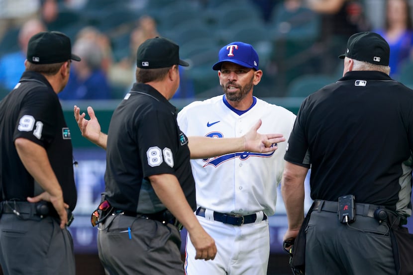 Texas Rangers manager Chris Woodward (8) argues with the umpires after an overturned call...