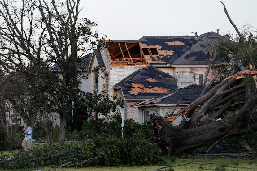 As the sun rises, homeowners emerge to survey damage from a tornado the night before near...