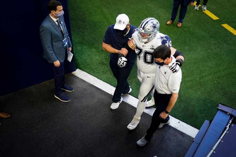Dallas Cowboys offensive guard Zack Martin is helped off the field after being injured...