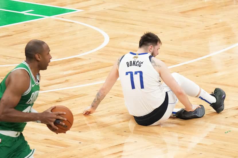 Dallas Mavericks guard Luka Doncic (77) grabs his ankle as Boston Celtics center Al Horford...