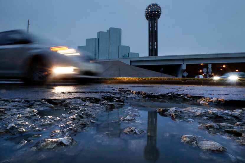 Reunion Tower is reflected in a rainwater-filled pothole near Reunion Boulevard in downtown...