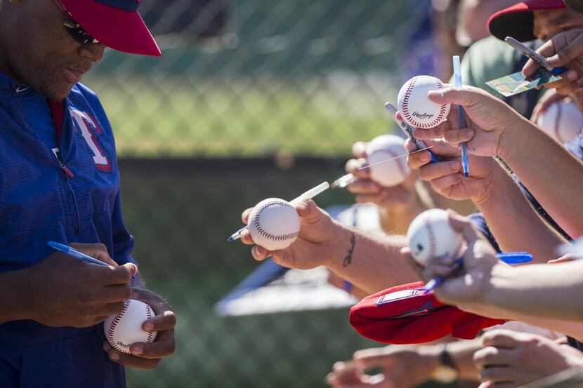 Texas Rangers third baseman Adrian Beltre signs autographs for fans during a spring training...