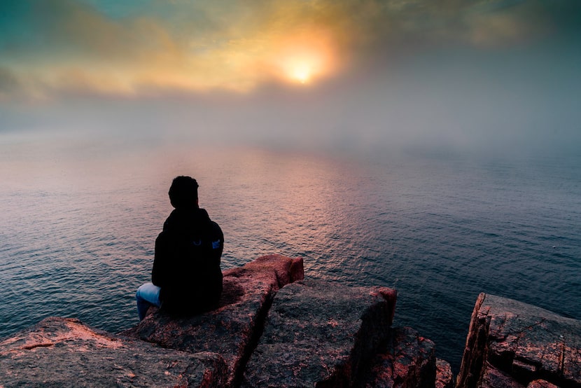 The sun rises amid the fog at Acadia National Park's Otter Cliffs. 