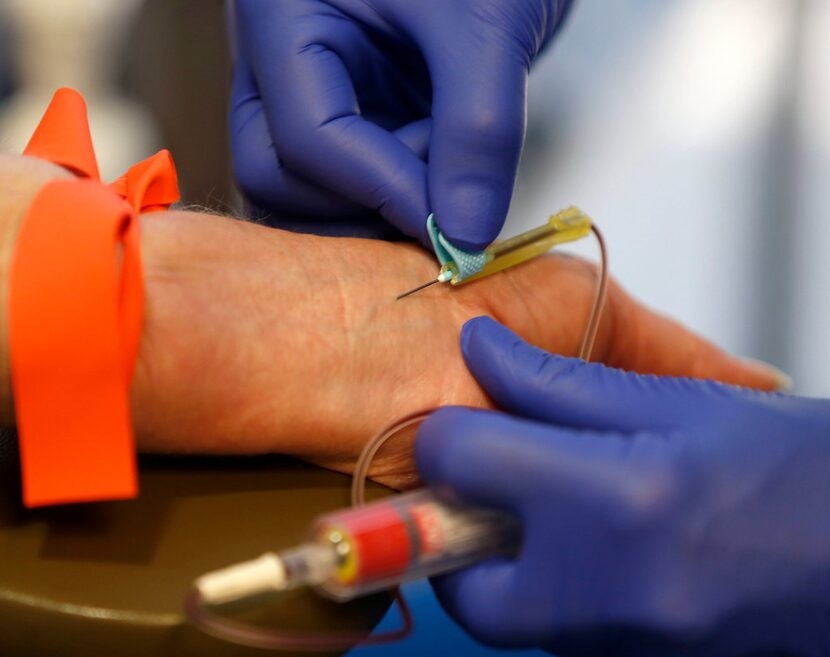 A phlebotomy technician, right, draws blood from a patient in Dallas on July 2. EMSI, an...