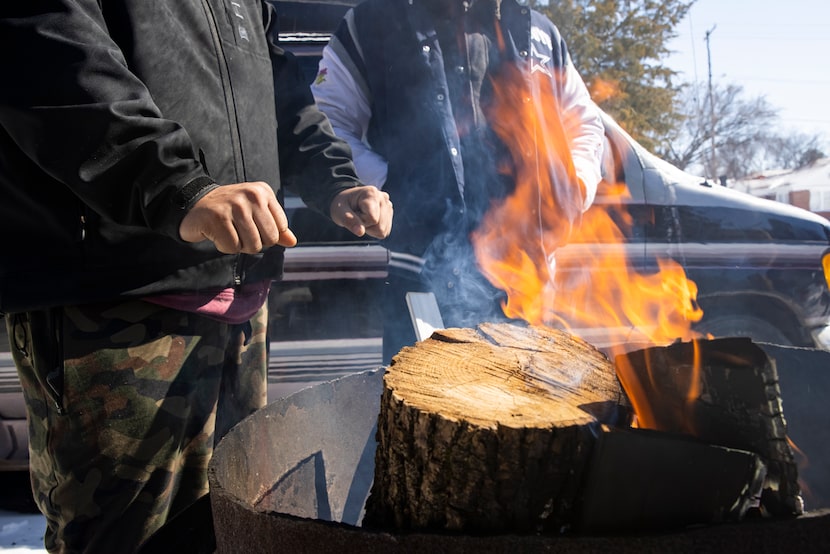 Alfredo Colón warmed his hands over a fire in front of his family’s East Dallas home on Feb....