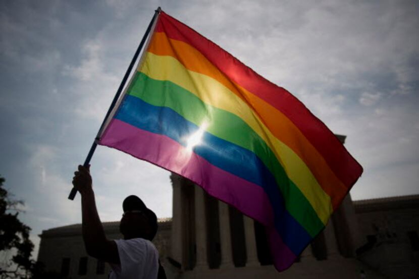  Demonstrator Carlos McKnight, from Washington, D.C., waved a rainbow flag outside the...