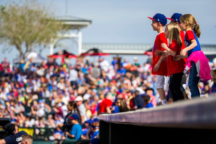 Children dance on top of the Texas Rangers dugout during the fourth inning of a spring...