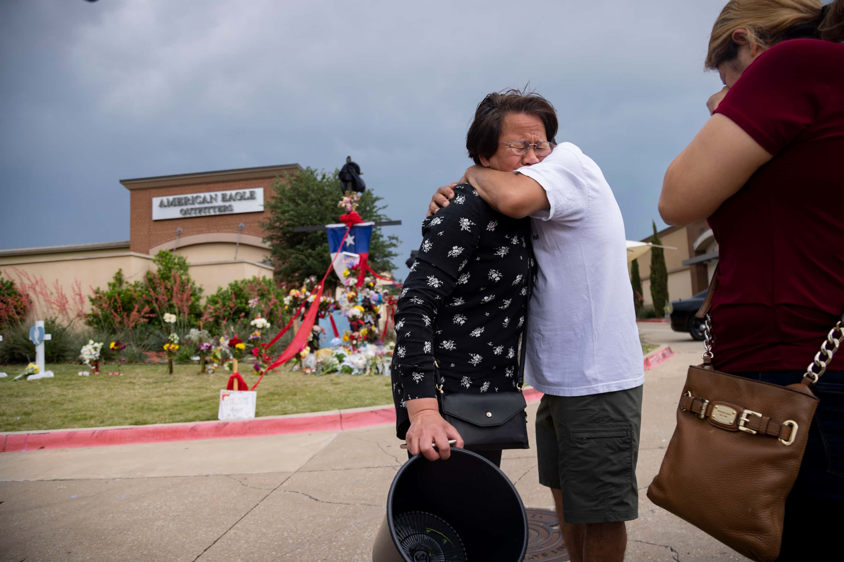 Gina Bennet (left) embraces Victor Ramirez as they reunite at the memorial outside the mall...