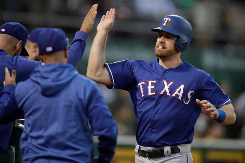 Texas Rangers' Logan Forsythe, right, is congratulated after scoring against the Oakland...