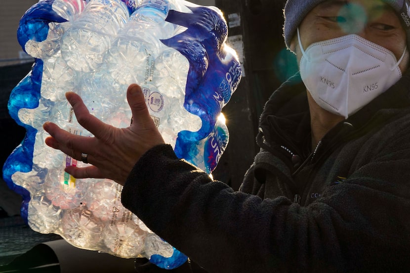 Volunteer George Tang helps unload two pallets of drinking water brought by the City of...