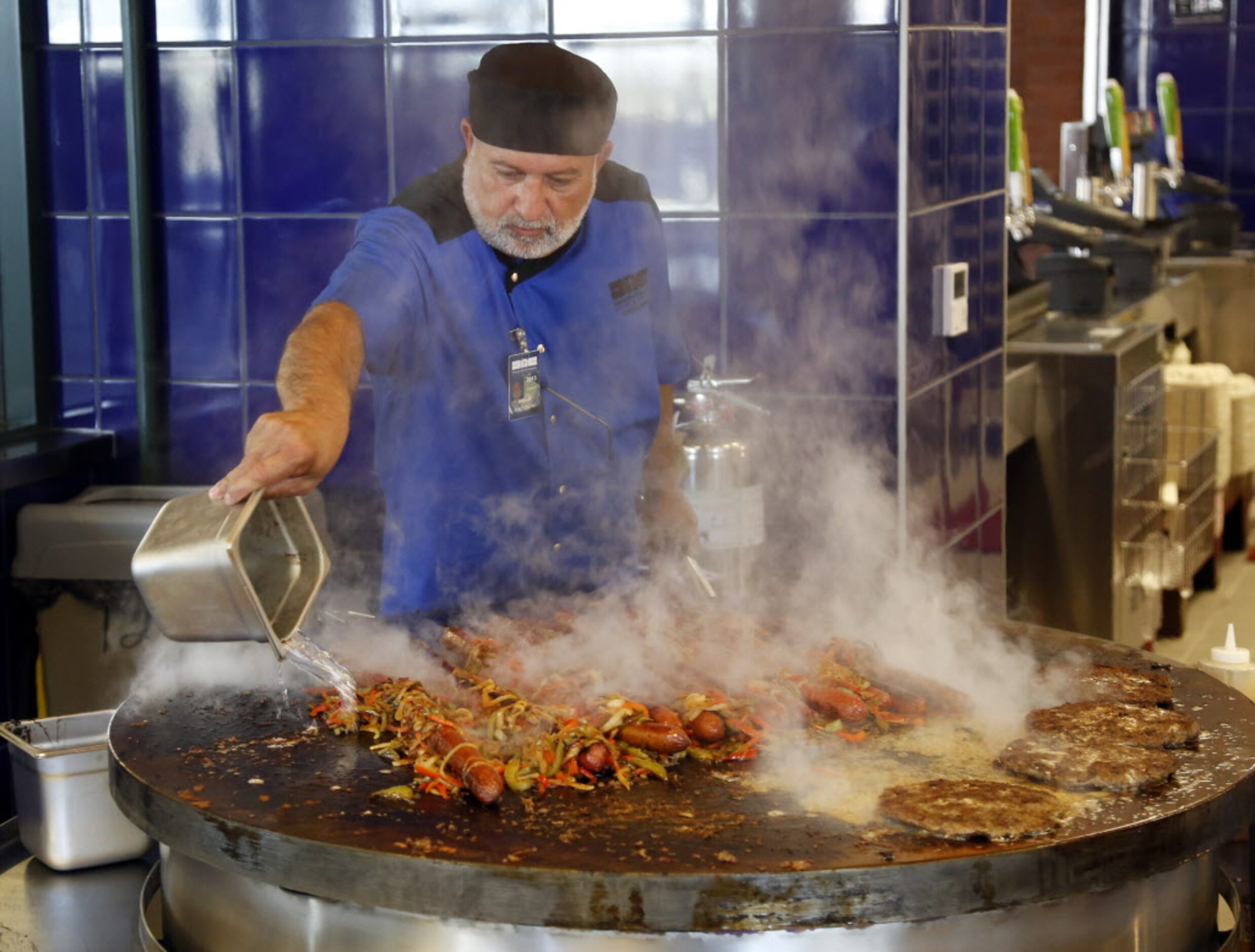 Sam Saleh grills foot-long dogs and other meats at Texas Rangers Ballpark in Arlington,...