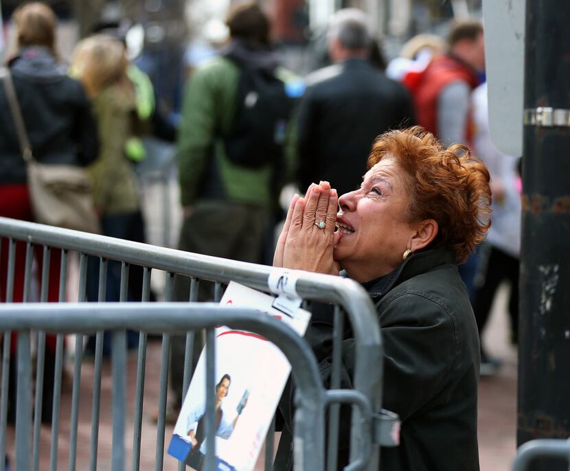 A distraught woman kneels in prayer after the explosions. “There are so many people without...