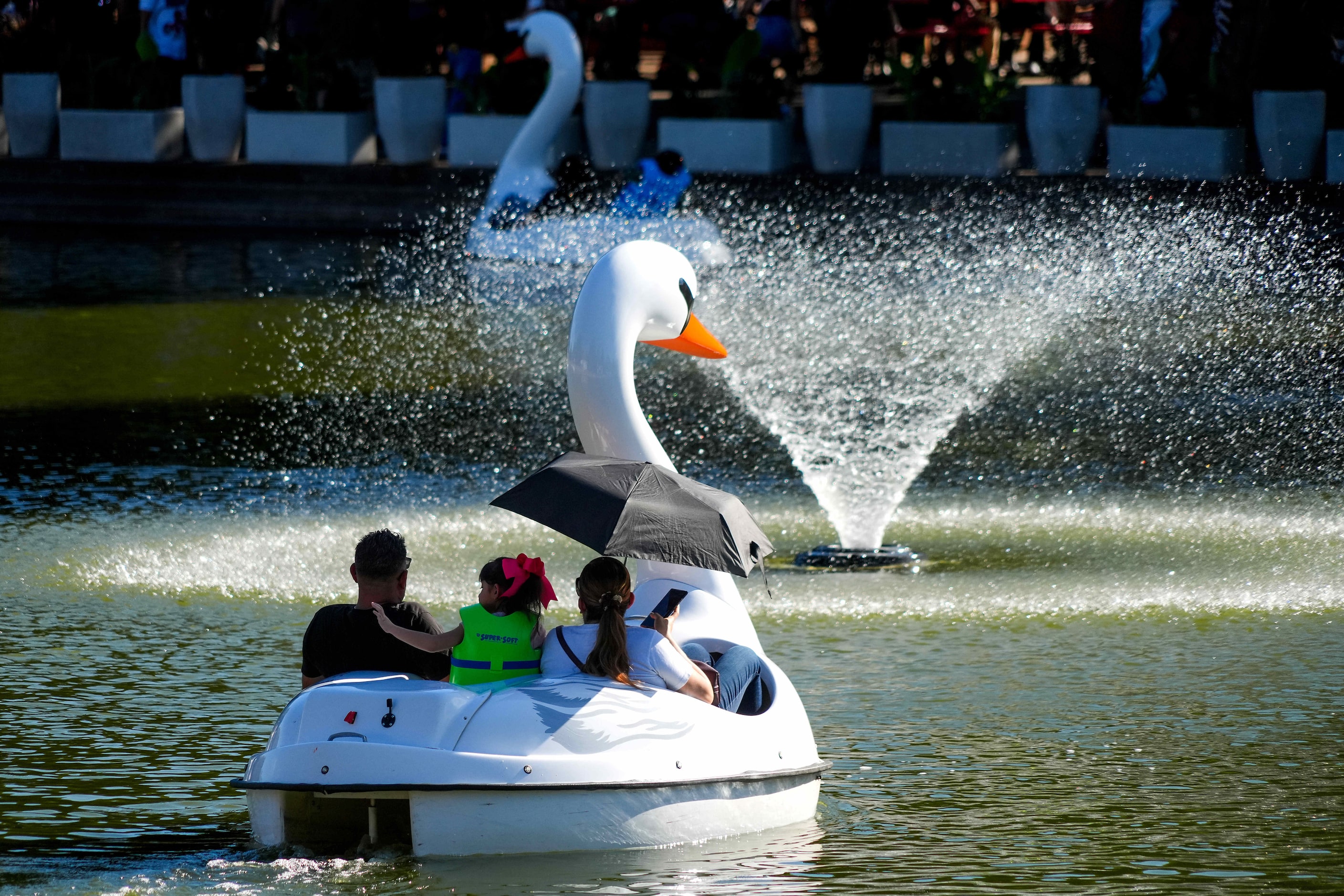 Fairgoers ride swan boats in the lagoon at the State Fair of Texas on Sunday, Sept. 29,...