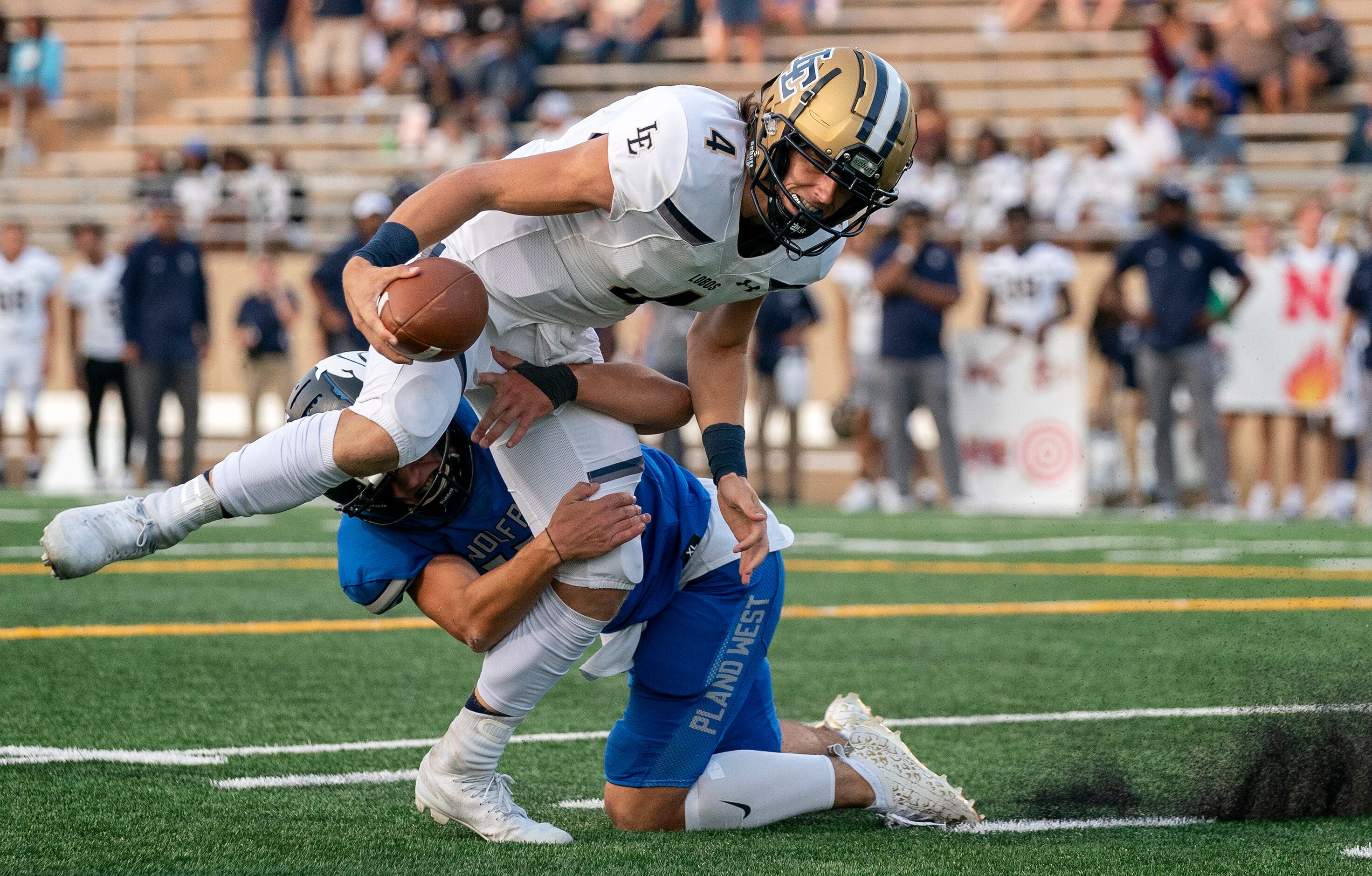 Little Elm senior quarterback John Mateer (4) fights through the tackle of Plano West junior...