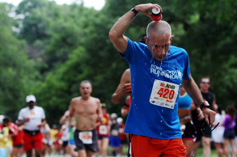 Paul Johnson, of Arlington, pours cool water on his head after passing the first water...