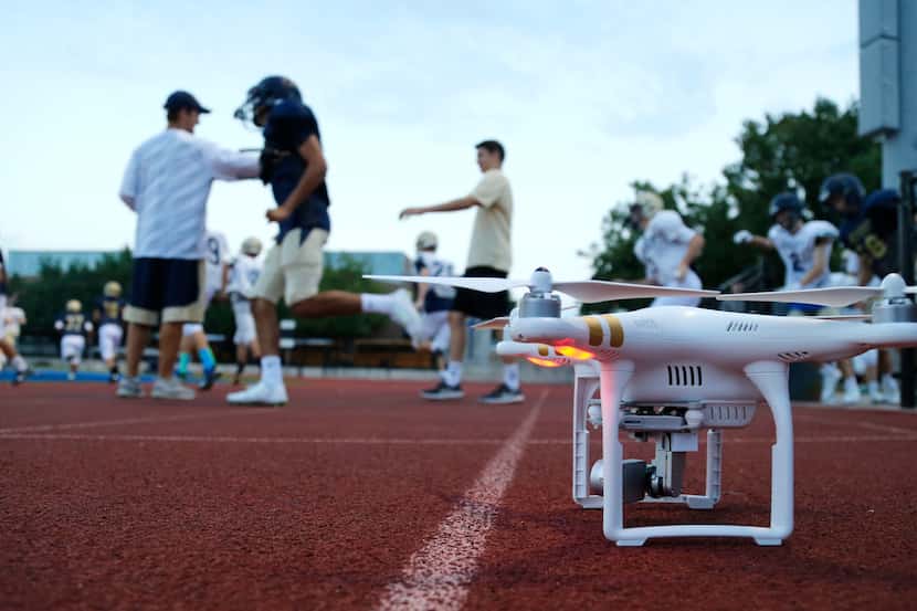 Jesuit football played take the field as a drone is powered up before football practice at...