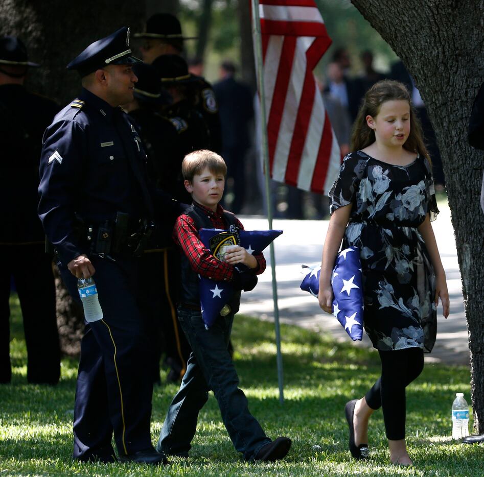 Dallas police officer Jaime Castro walks with Sorcha Ahrens, 10, (right) and Magnus Ahrens,...