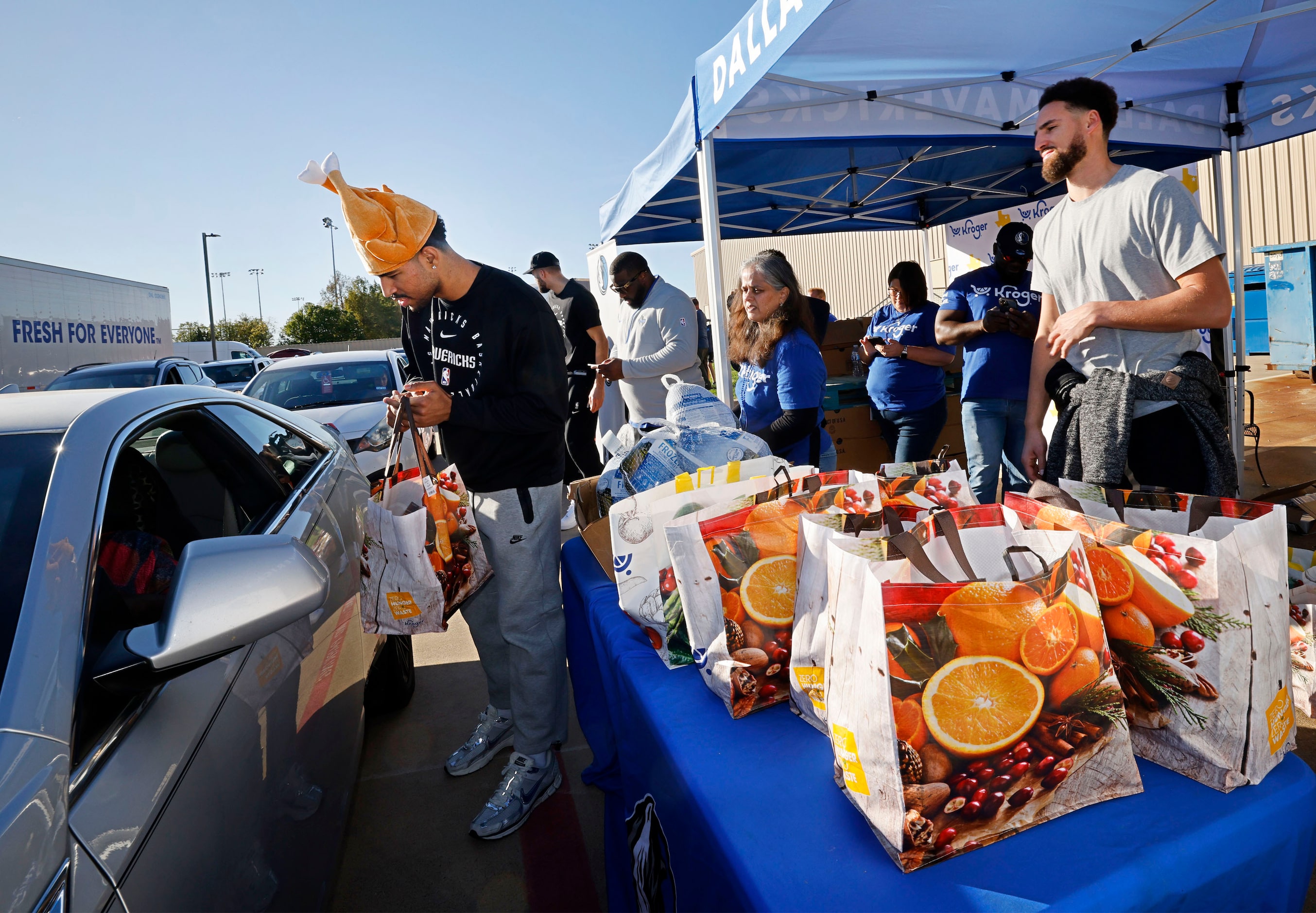 Dallas Mavericks guard Quentin Grimes, left, hands a Thanksgiving  meal bag to a motorist...