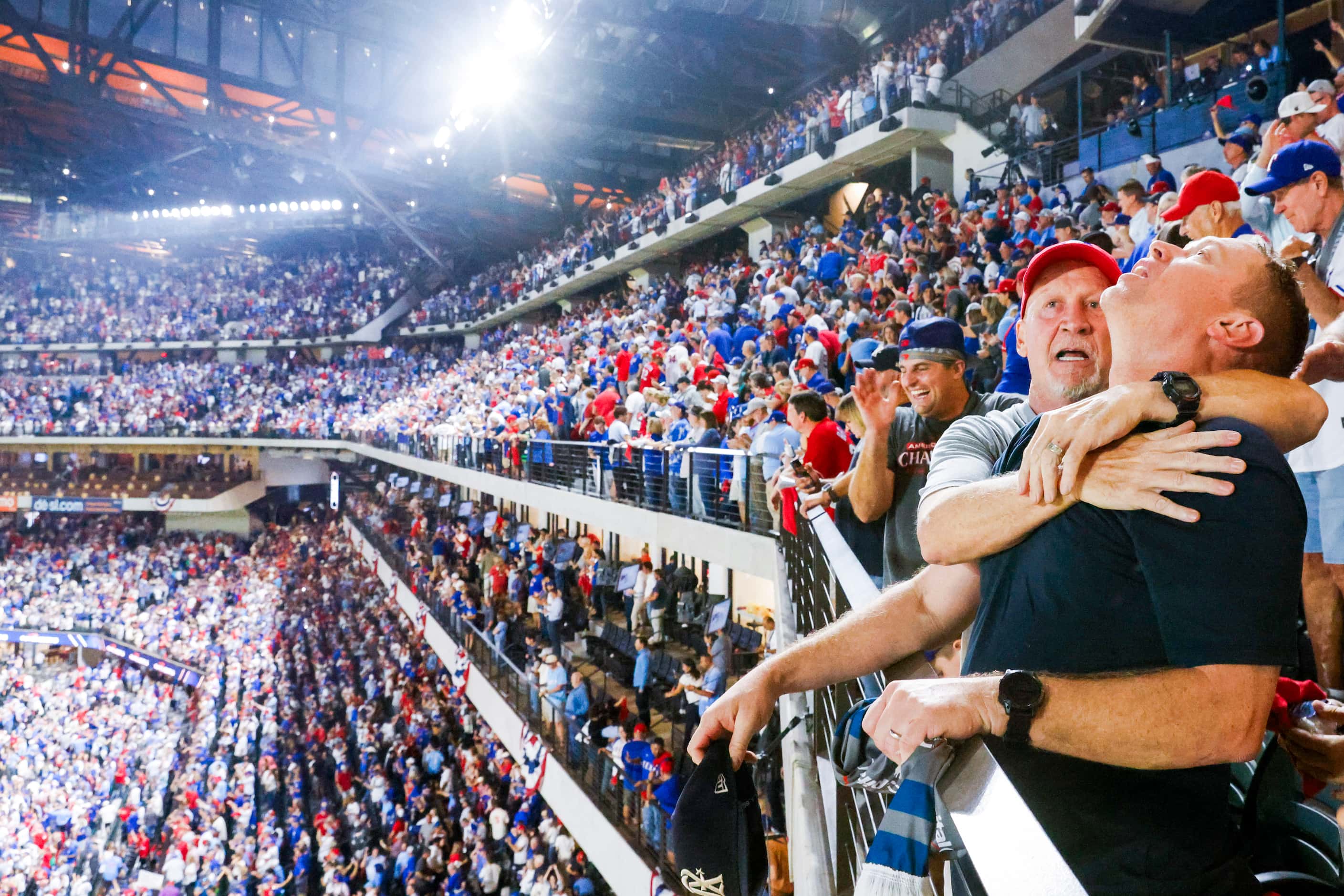 Texas Rangers fans Brian Crowley (facing) and Nick Wilhelmson react after Adolis Garcia’s...