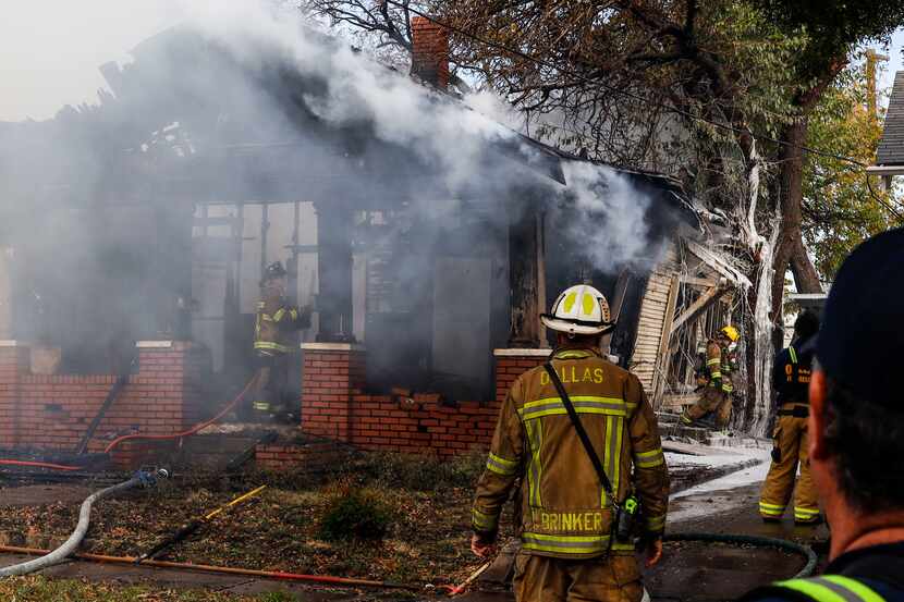 Dallas firefighters extinguish flames at a house in the 800 block of Centre Street in north...