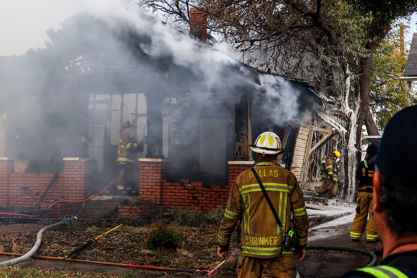 Dallas firefighters extinguish flames at a house in the 800 block of Centre Street in north...