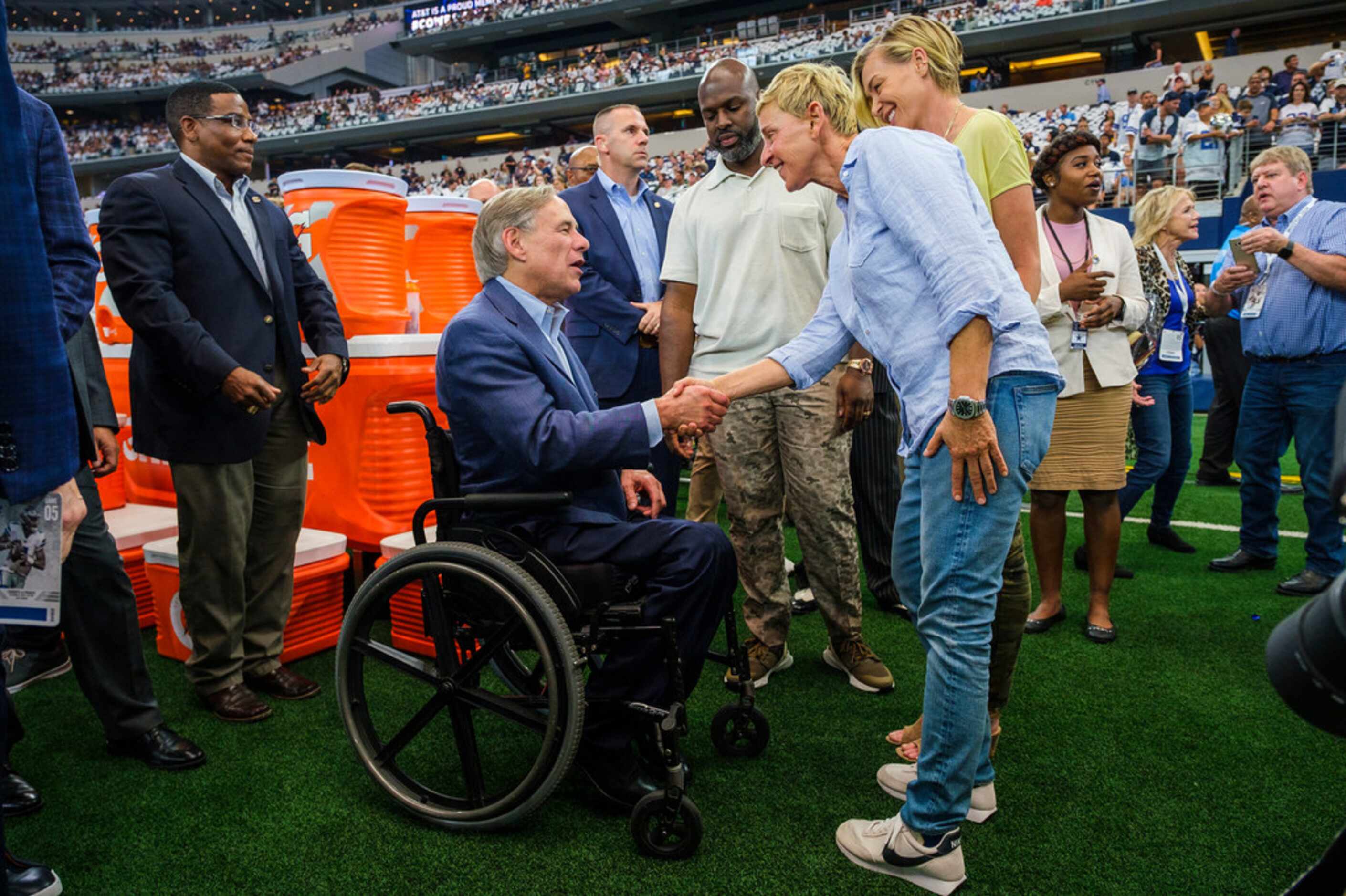 Ellen DeGeneres talks with Texas Gov. Greg Abbott before an NFL football game between the...
