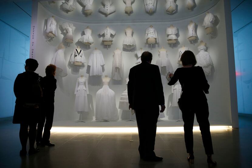 Visitors look at some of the Dior pieces in the "Office of Dreams" area of the fashion...