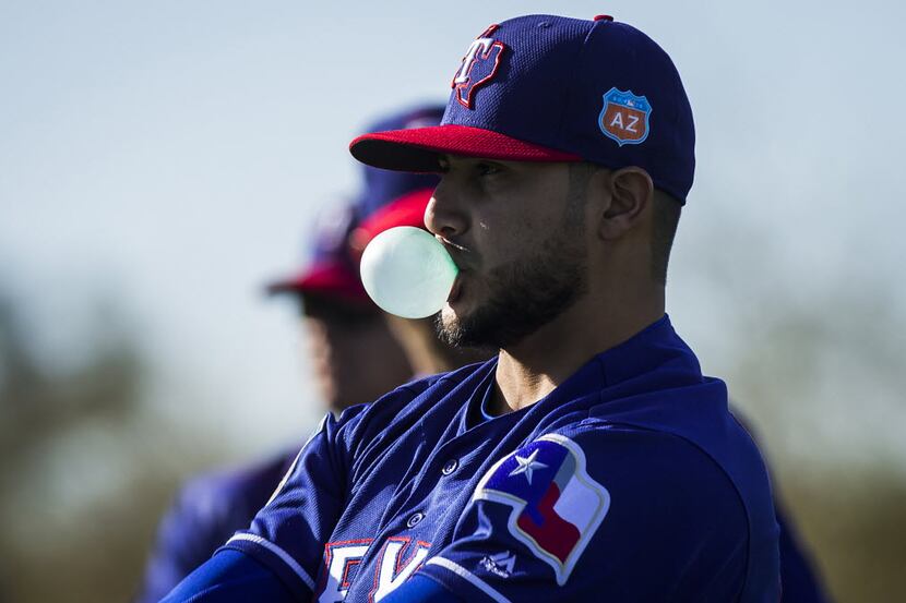 Texas Rangers pitcher Martin Perez blows a bubble while stretching with teammates during a...