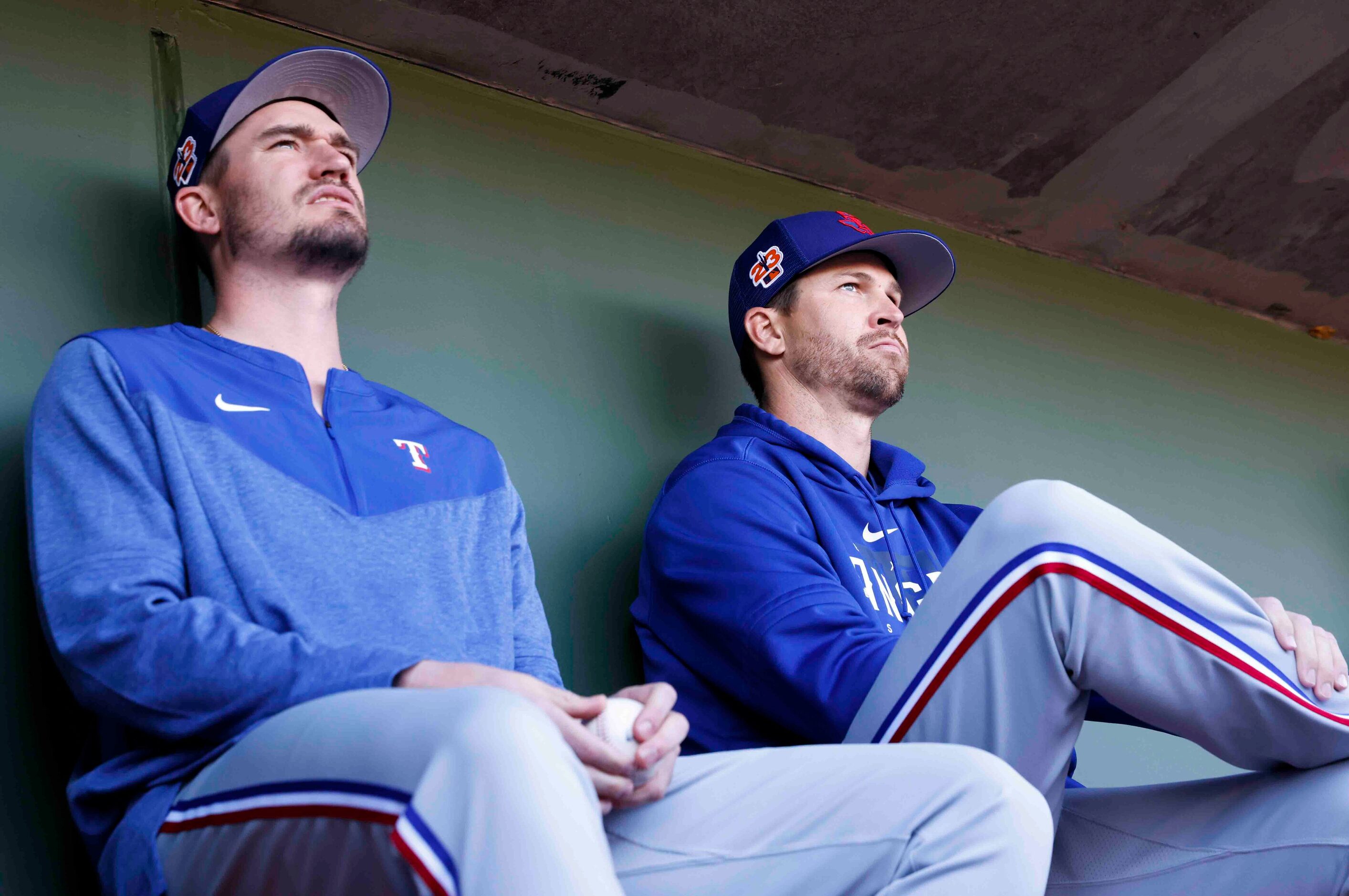 Texas Rangers pitchers Andrew Heaney, left, and Jacob deGrom sit in the dugout during a...